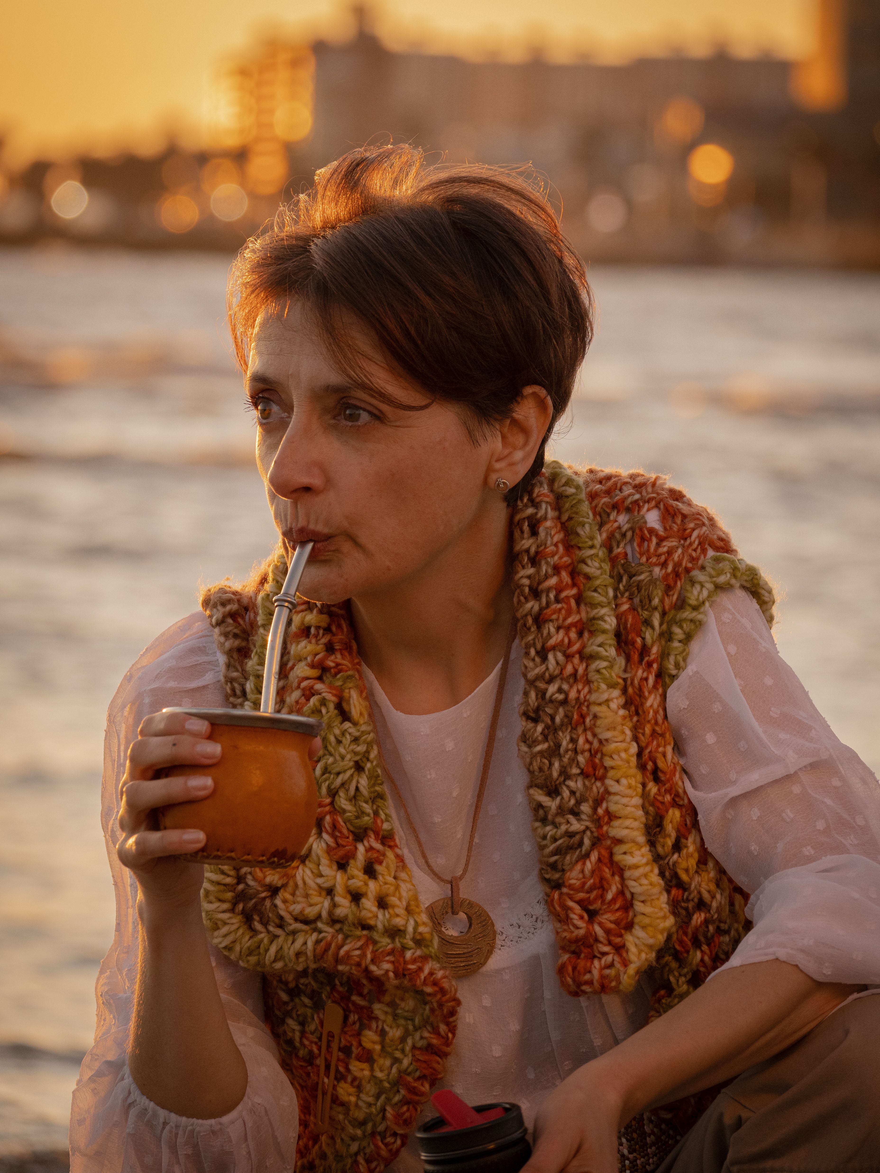 A woman enjoys yerba mate by the waterfront during sunset in Montevideo, Uruguay.