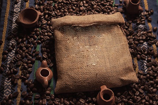 Burlap sack filled with coffee beans, surrounded by pottery and traditional textile.