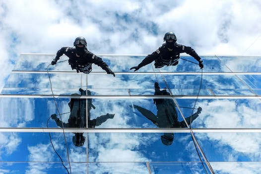 Gendarmerie officers rappelling down a glass building with sky reflections.