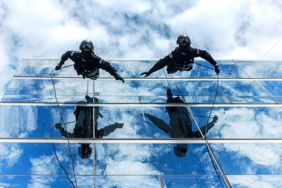 Free 在多云的天空下建筑玻璃墙上的两个人 Stock Photo