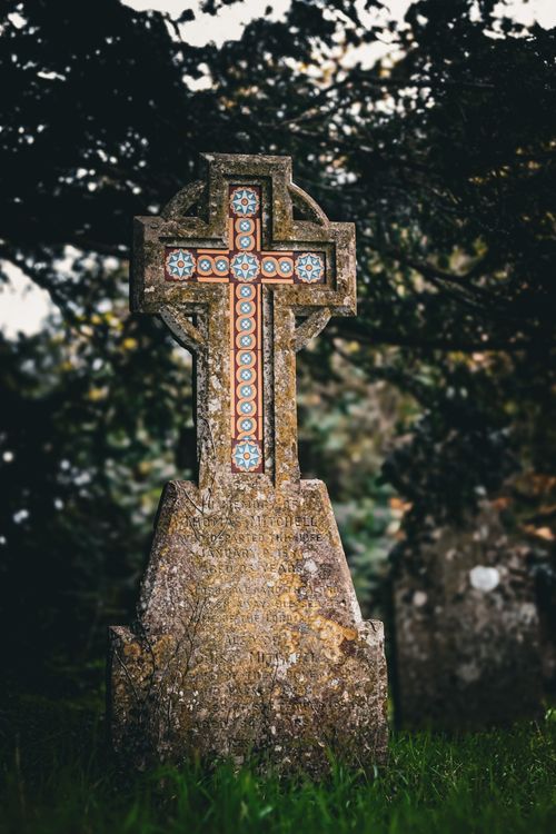 Free Ancient weathered gravestone featuring a Celtic cross, located in a peaceful cemetery in Shaftesbury, England. Stock Photo