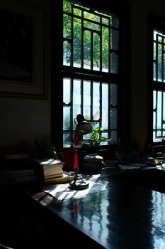 A serene home office space with a desk, books, and natural light streaming through the window.