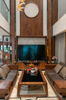 Elegant living room with wooden accents, plush sofas, and a large TV creating a cozy ambiance.