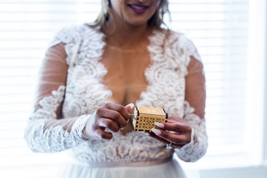 Close-up of a bride holding a decorative wooden box wearing a lace wedding gown