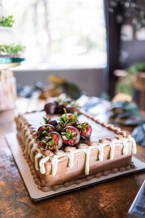 Free Mouthwatering chocolate cake adorned with fresh strawberries and cream drizzles, perfect for celebrations. Stock Photo