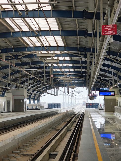 Spacious, modern train station with empty platforms under a clear sky.