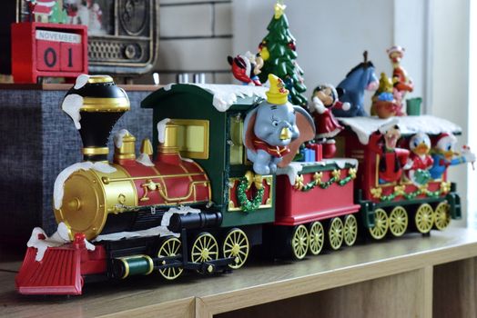Colorful toy train featuring Disney characters and holiday decorations on a shelf.