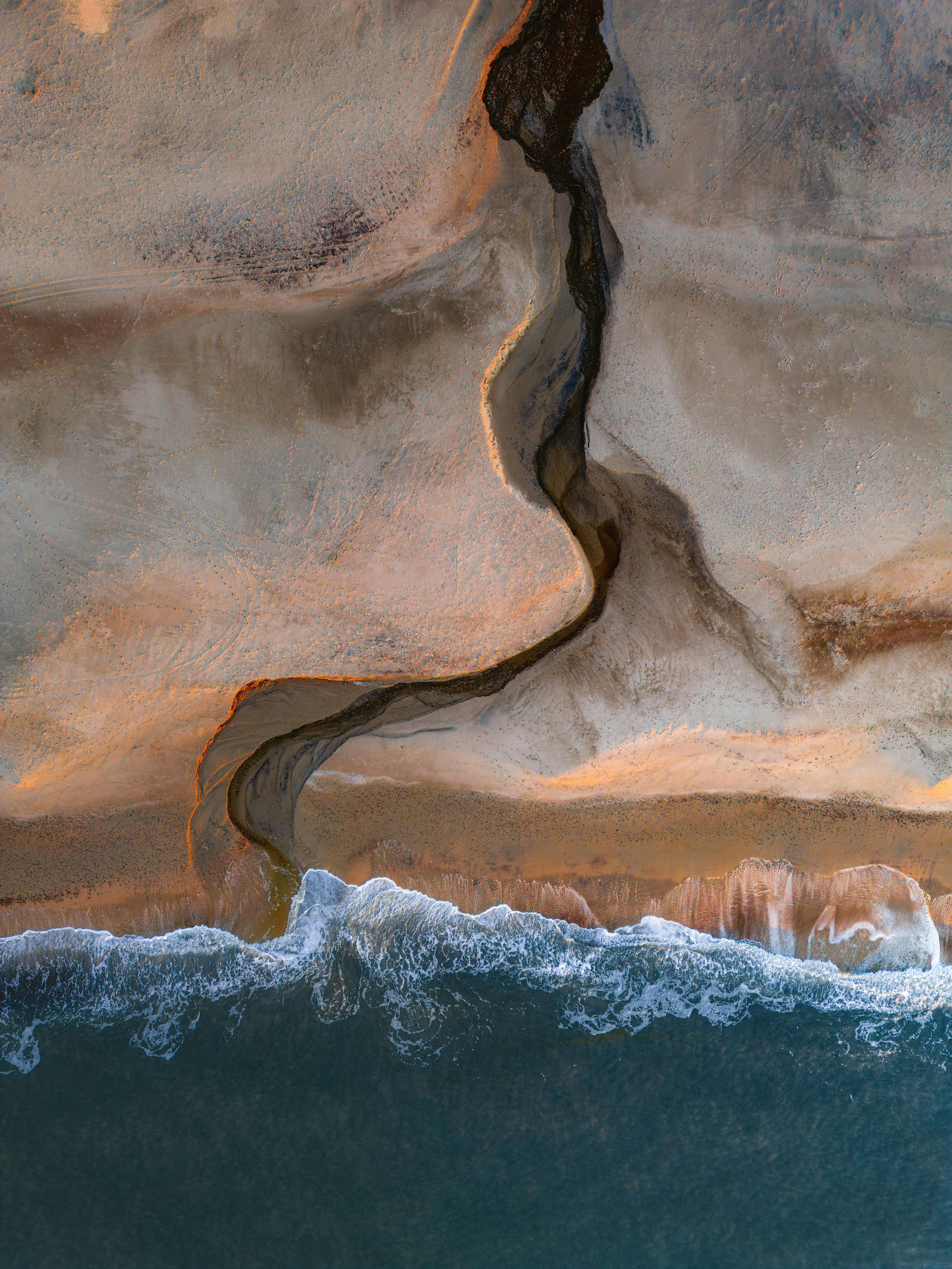 Captivating aerial view of Denmark's coastline at sunset, with stunning patterns and ocean waves.