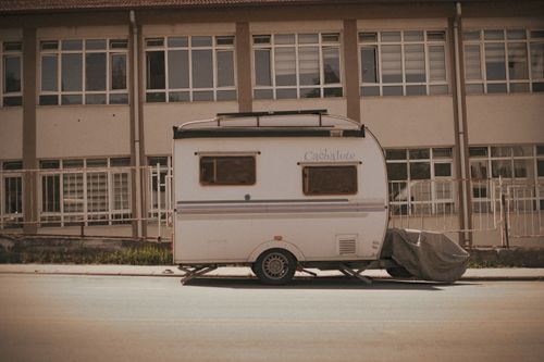 Free A retro-style caravan parked in front of a building during daylight. Stock Photo