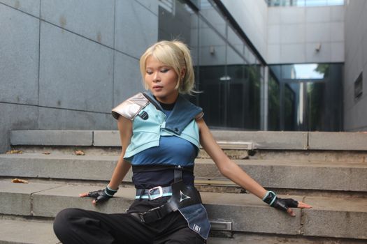 Model poses in futuristic attire on urban steps. Trendy and sleek fashion.