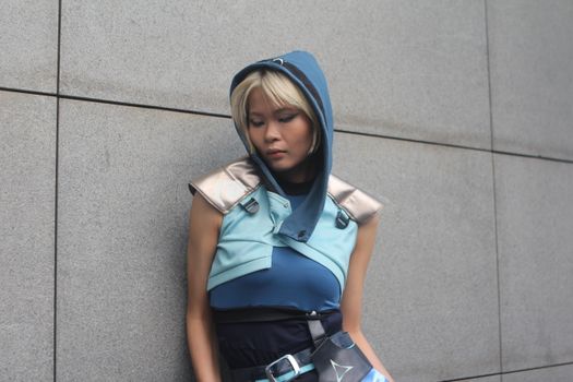 Person in a blue fantasy costume against a concrete wall.