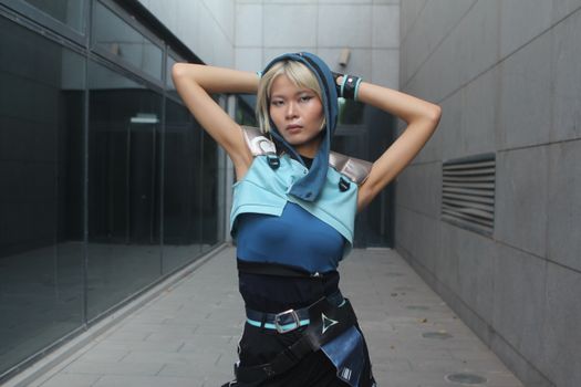 Fashionable young woman poses confidently in urban setting with modern architecture.