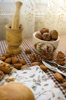 Cozy kitchen scene featuring nuts, mortar and pestle, nutcracker on a checkered tablecloth.