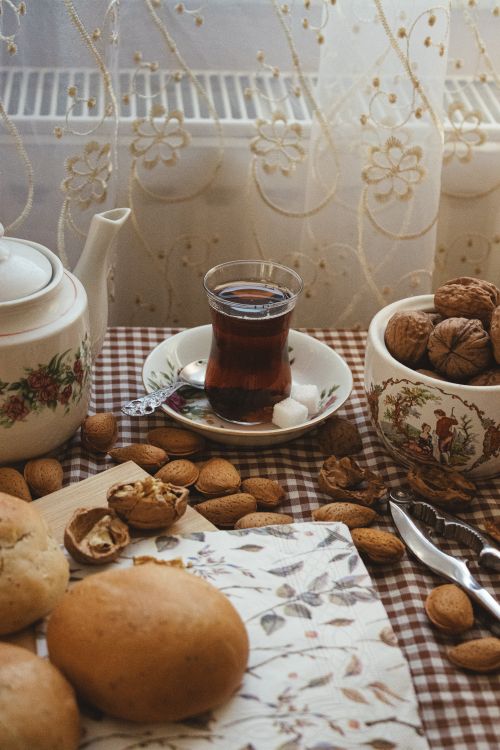 Free A warm scene of tea, nuts, and pastries on a checkered tablecloth by a window. Stock Photo