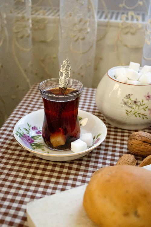 Free A glass of tea with sugar cubes and walnuts on a checkered tablecloth, exuding warmth and coziness. Stock Photo