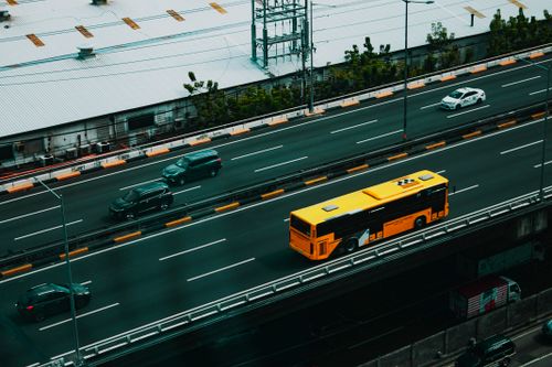 Free From above of modern yellow bus and various cars driving on asphalt road in city Stock Photo