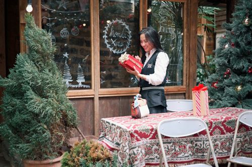 Free Woman joyfully holds a Christmas gift in a festive outdoor setting. Stock Photo