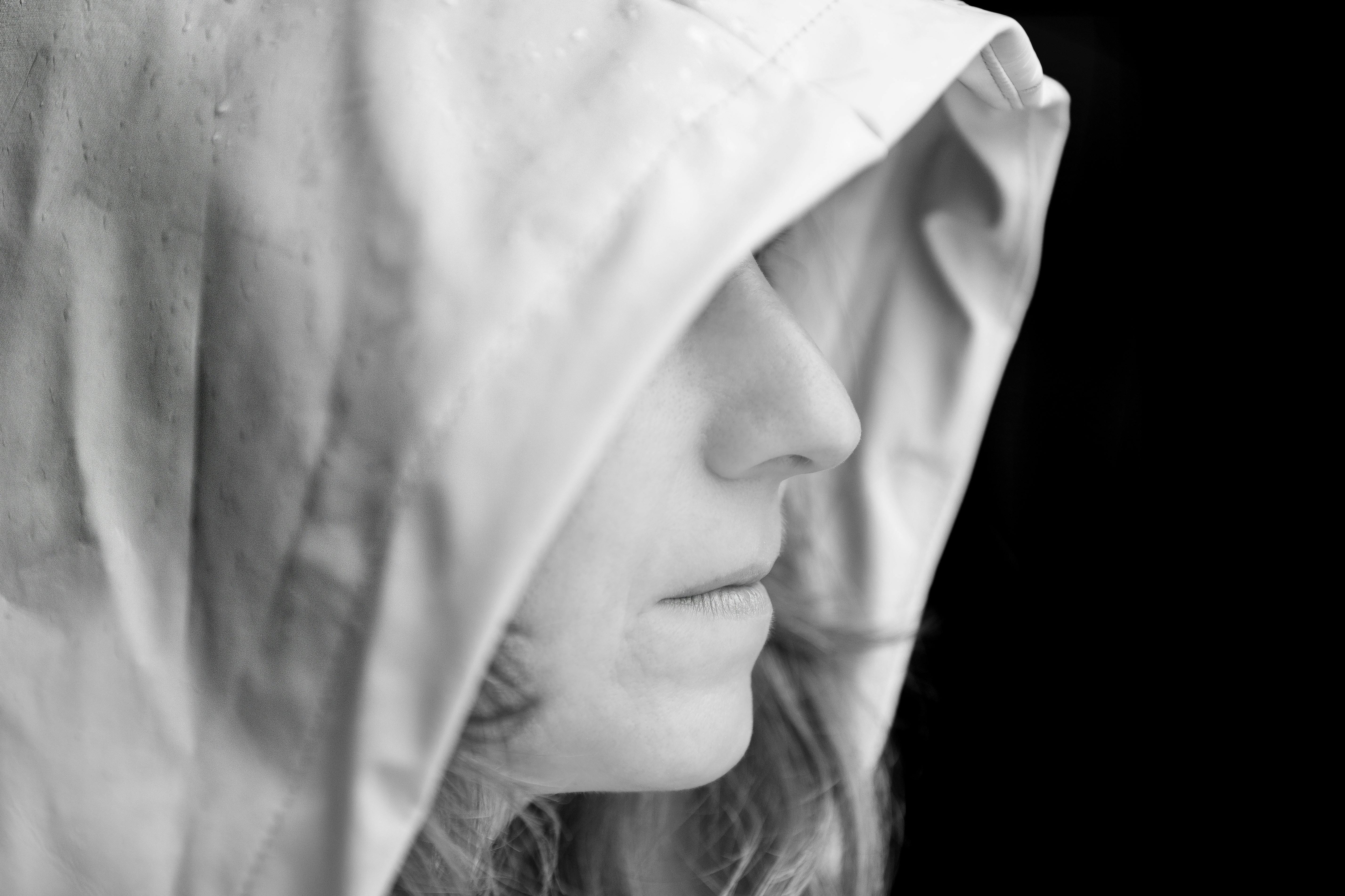 Black and white side profile of an adult wearing a hood, evoking a mysterious and introspective mood.