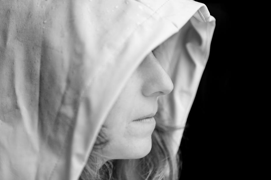 Black and white side profile of an adult wearing a hood, evoking a mysterious and introspective mood.