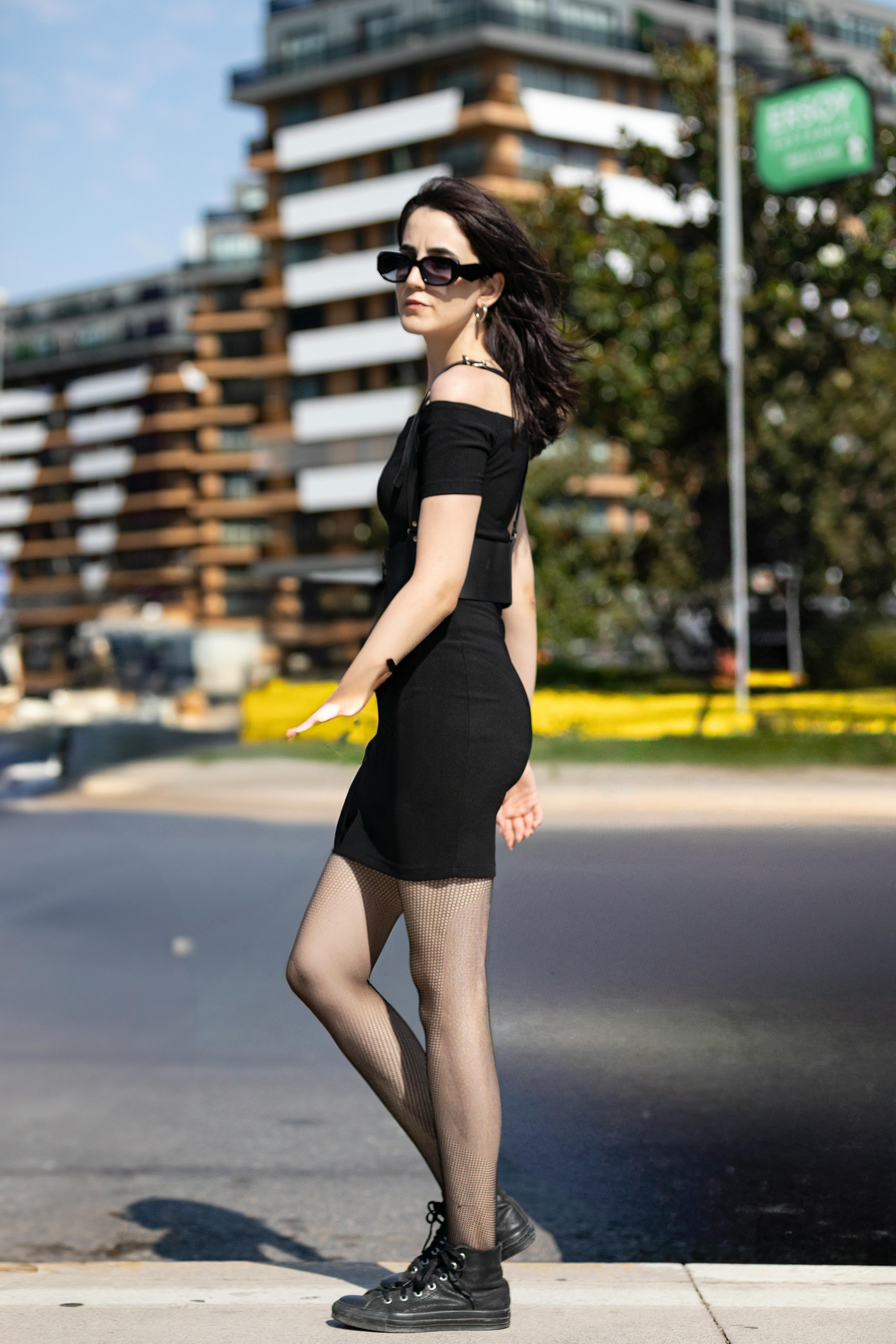 A fashionable woman in modern attire walks confidently in an urban city environment during the day.