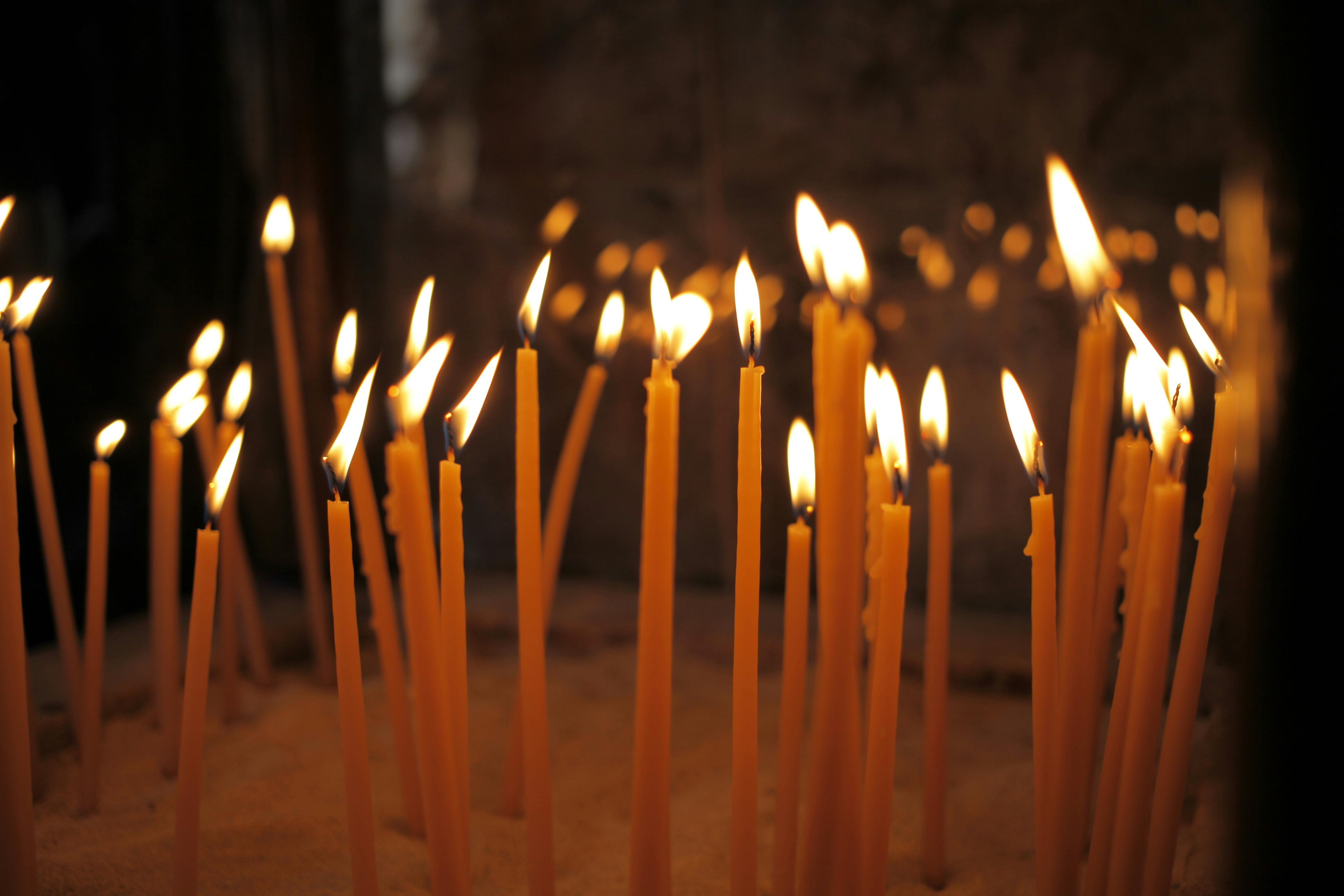 A serene scene of lit votive candles during a religious ceremony in a Larnaka church.