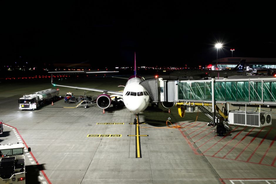 Photo by Eran Menashri A large passenger airplane is docked at an airport terminal under night skies, ready for its next flight.