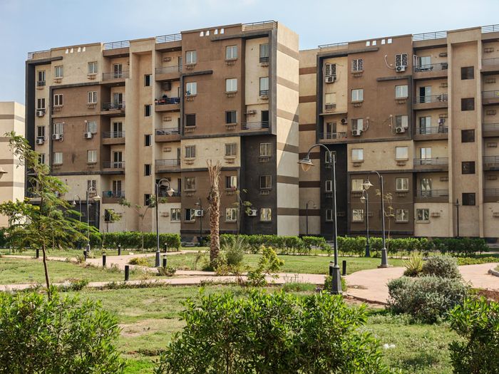 Jardín comunitario con césped y arbustos entre bloques de viviendas