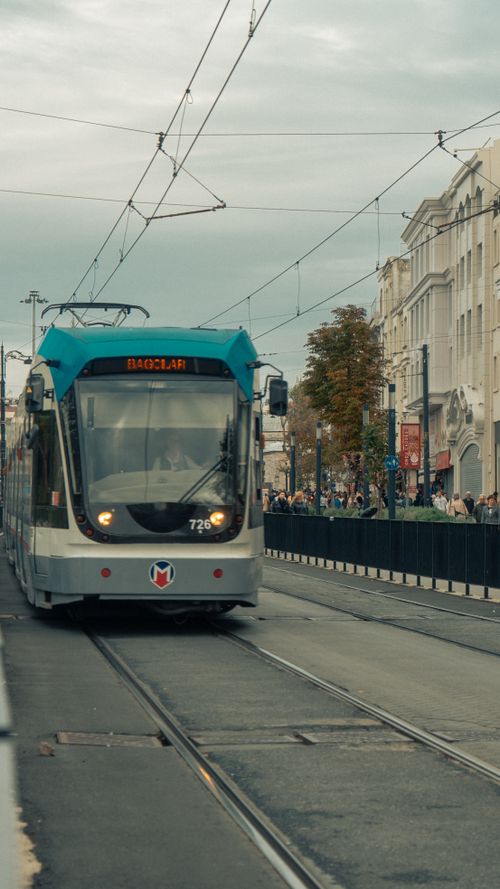 Free A bustling city street scene with a modern tram and urban architecture during an overcast day. Stock Photo