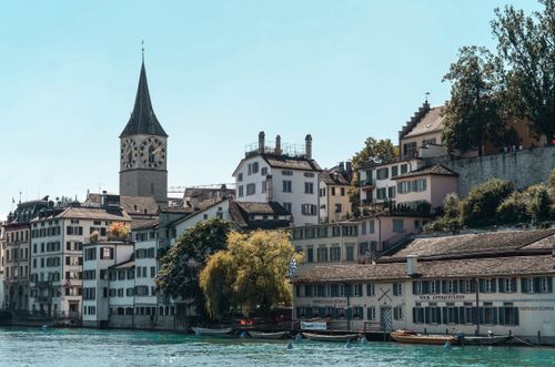 Free Scenic view of Zürich's iconic architecture along the Limmat River with church tower and classic Swiss buildings. Stock Photo