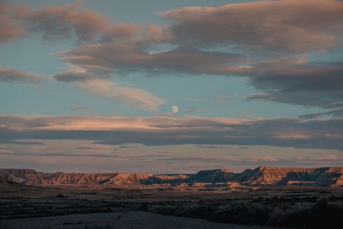 Free Breathtaking view of a desert landscape at twilight with the moon visible in a serene sky. Stock Photo