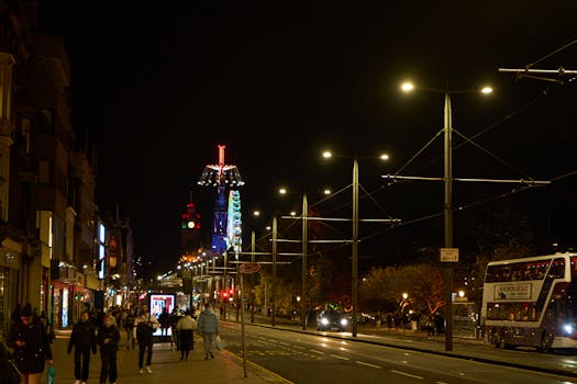A dynamic nighttime street scene in Edinburgh with festive lights and bustling activity.