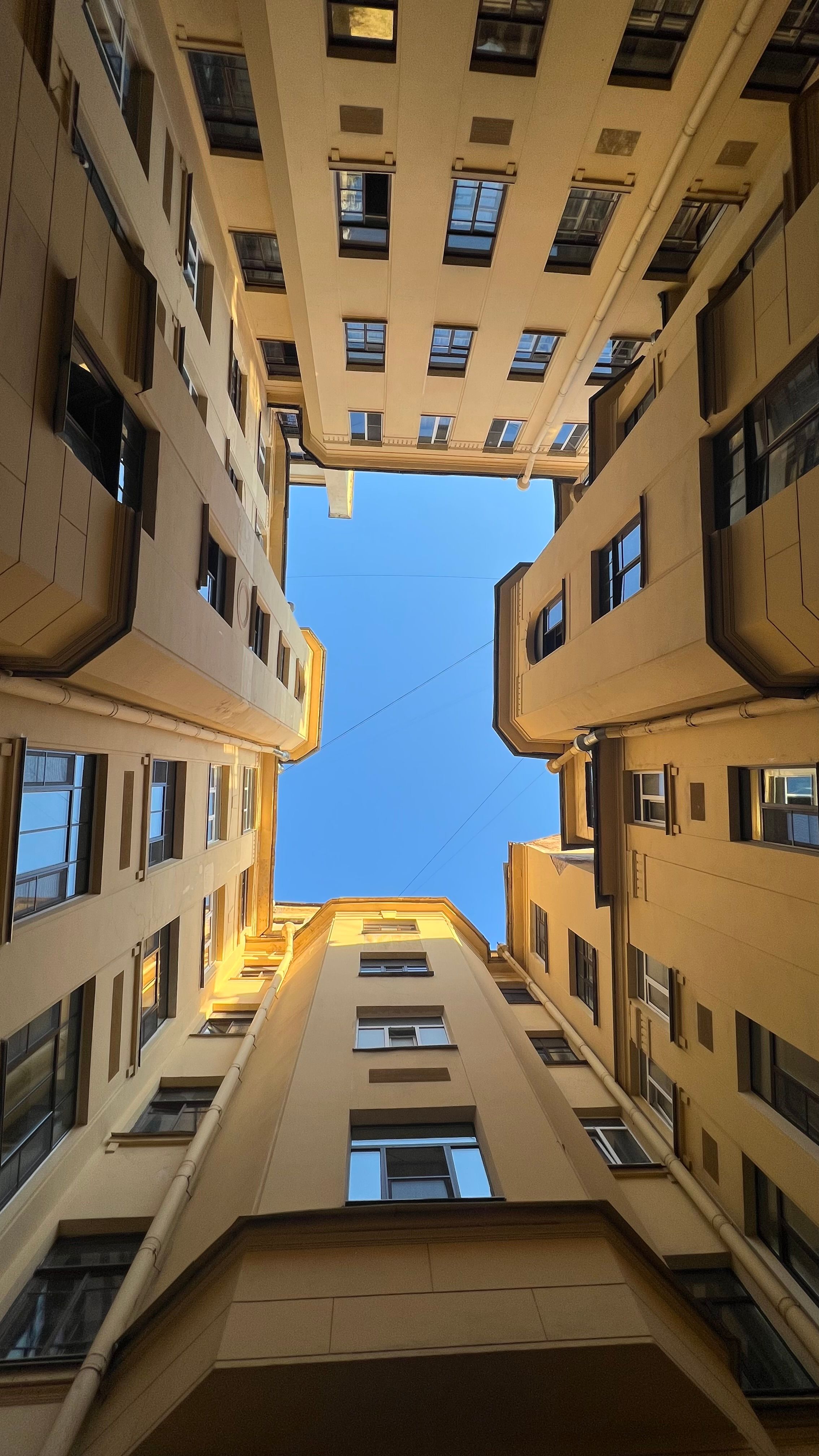 Dramatic upward view of urban courtyard with clear sky.