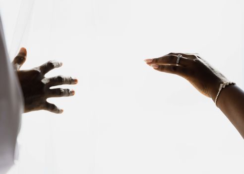 Hands in elegant gesture showcasing wedding rings and jewelry. Minimalist and artistic style with bright tones.