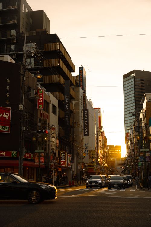 Free Urban street view in Tokyo with cars and people at sunset, vibrant atmosphere. Stock Photo
