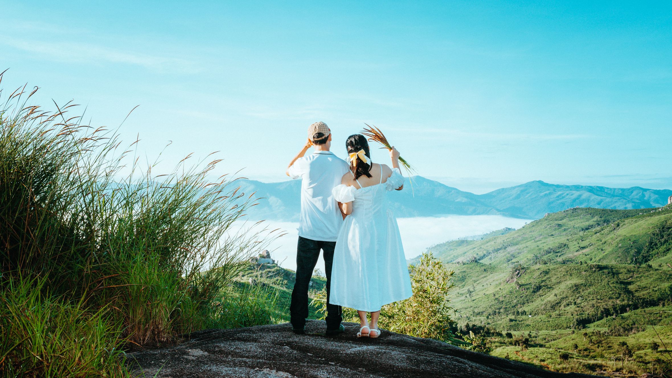 A couple standing on a mountain in Kon Tum, Vietnam, admiring a breathtaking landscape.