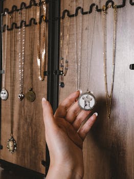 Close-up of a hand selecting a necklace from a wooden jewelry display, showcasing elegance and style.