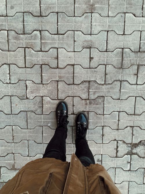 Free View from above of a person standing on a textured concrete pavement. Stock Photo