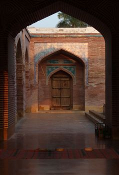 Explore the intricate architecture of a historical mosque courtyard featuring archways and a wooden door.