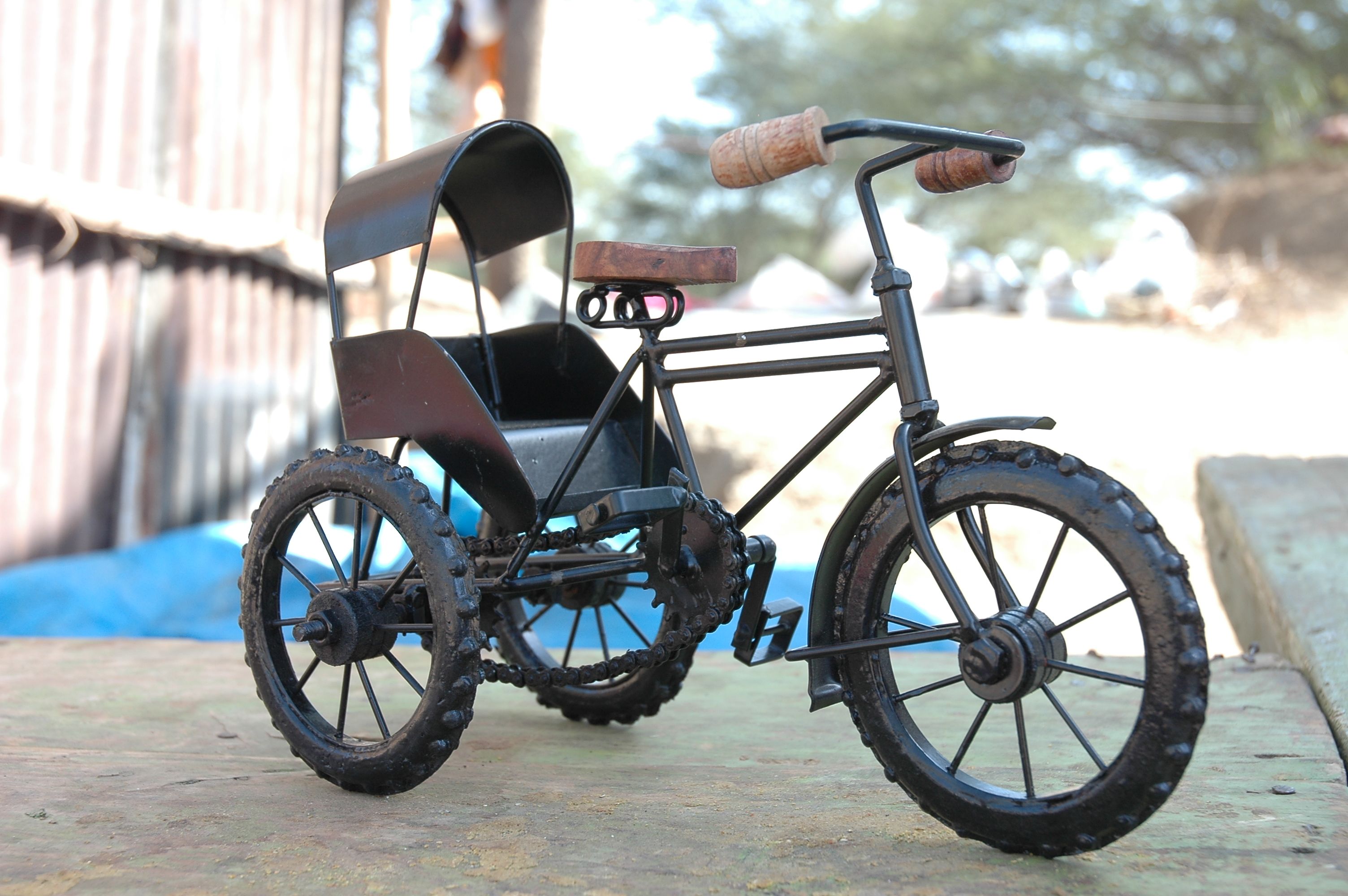 Vintage metal tricycle model displayed outdoors on a sunny day.