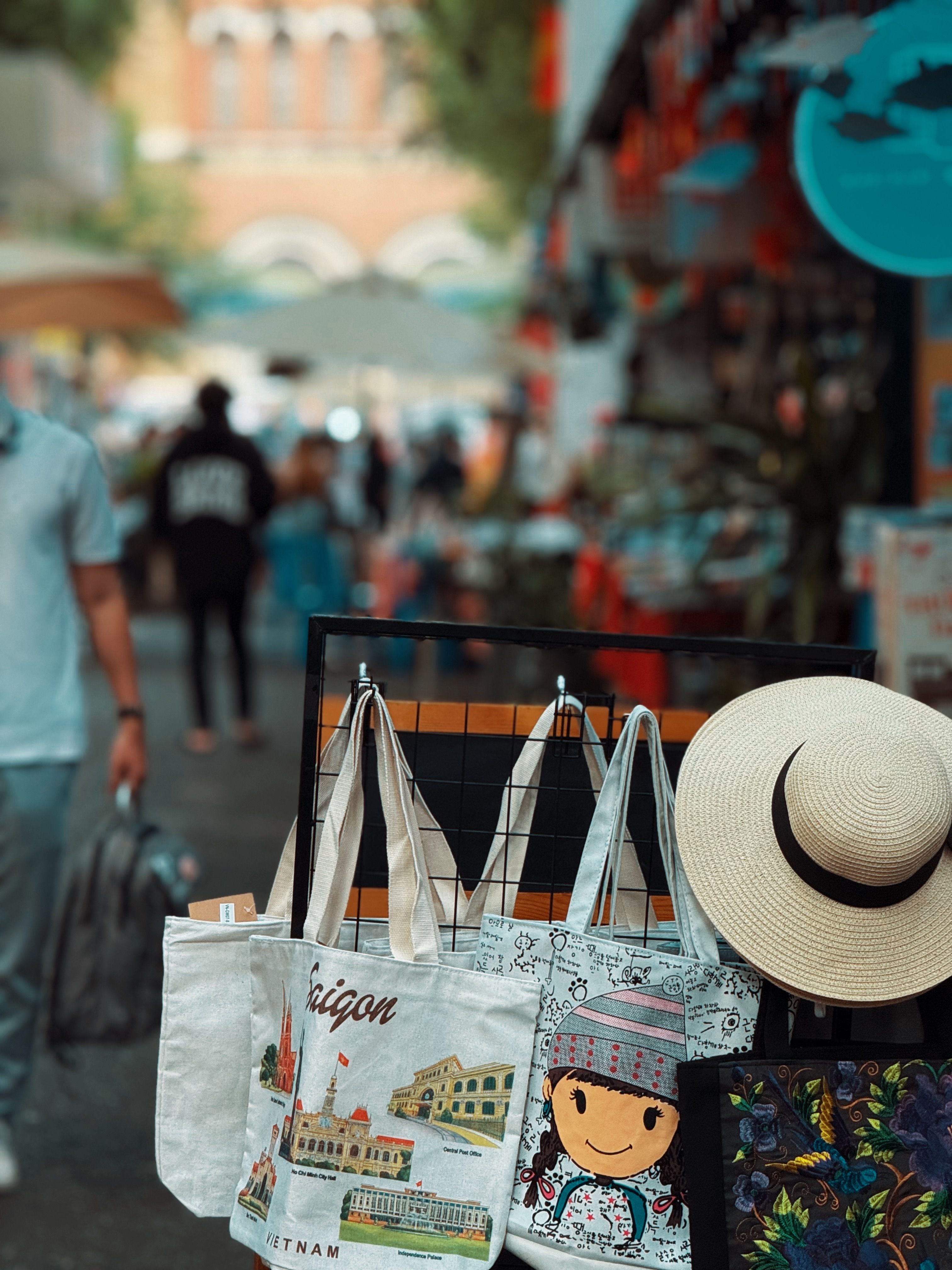 Colorful market stall in bustling street with variety of tote bags and straw hat. - Expert Tips for Selecting the Perfect Handbag