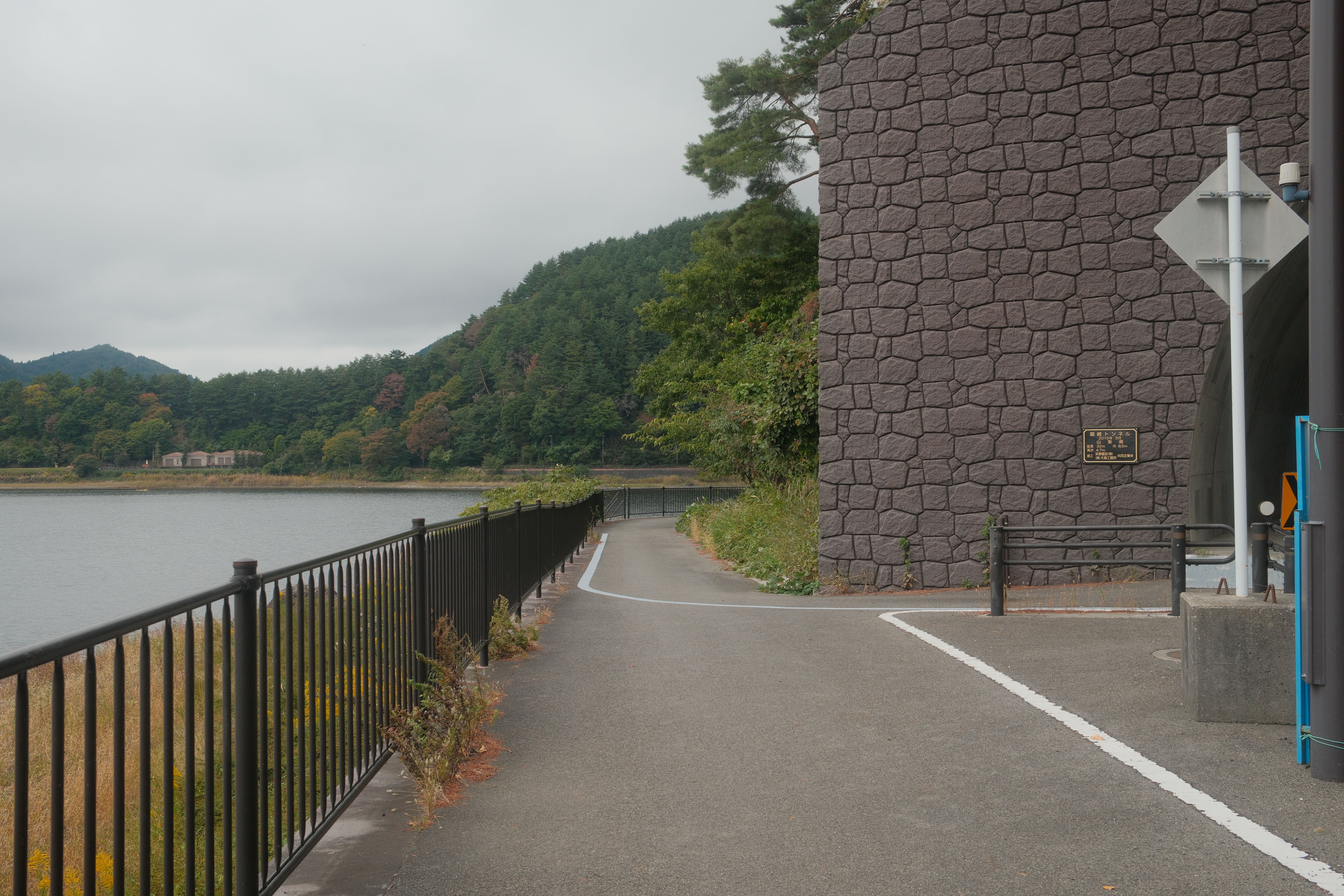 Quiet lakeside pathway at Lake Kawaguchi with lush autumn foliage and serene mountain views.