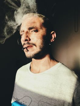 一张男子吸烟的特写肖像，阴影浓重，烟雾弥漫