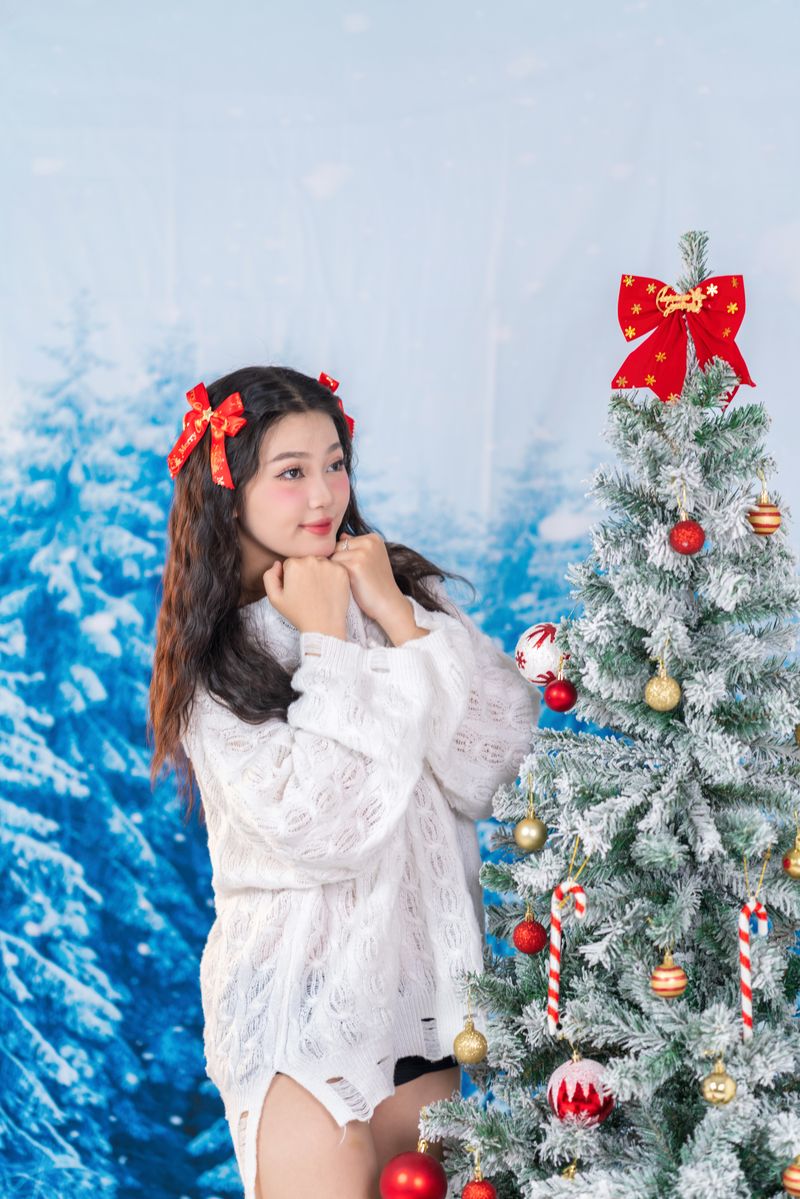 Woman in winter attire beside a Christmas tree