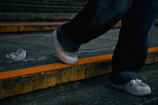 A person steps past an abandoned tiara on gritty urban steps, hinting at a story.