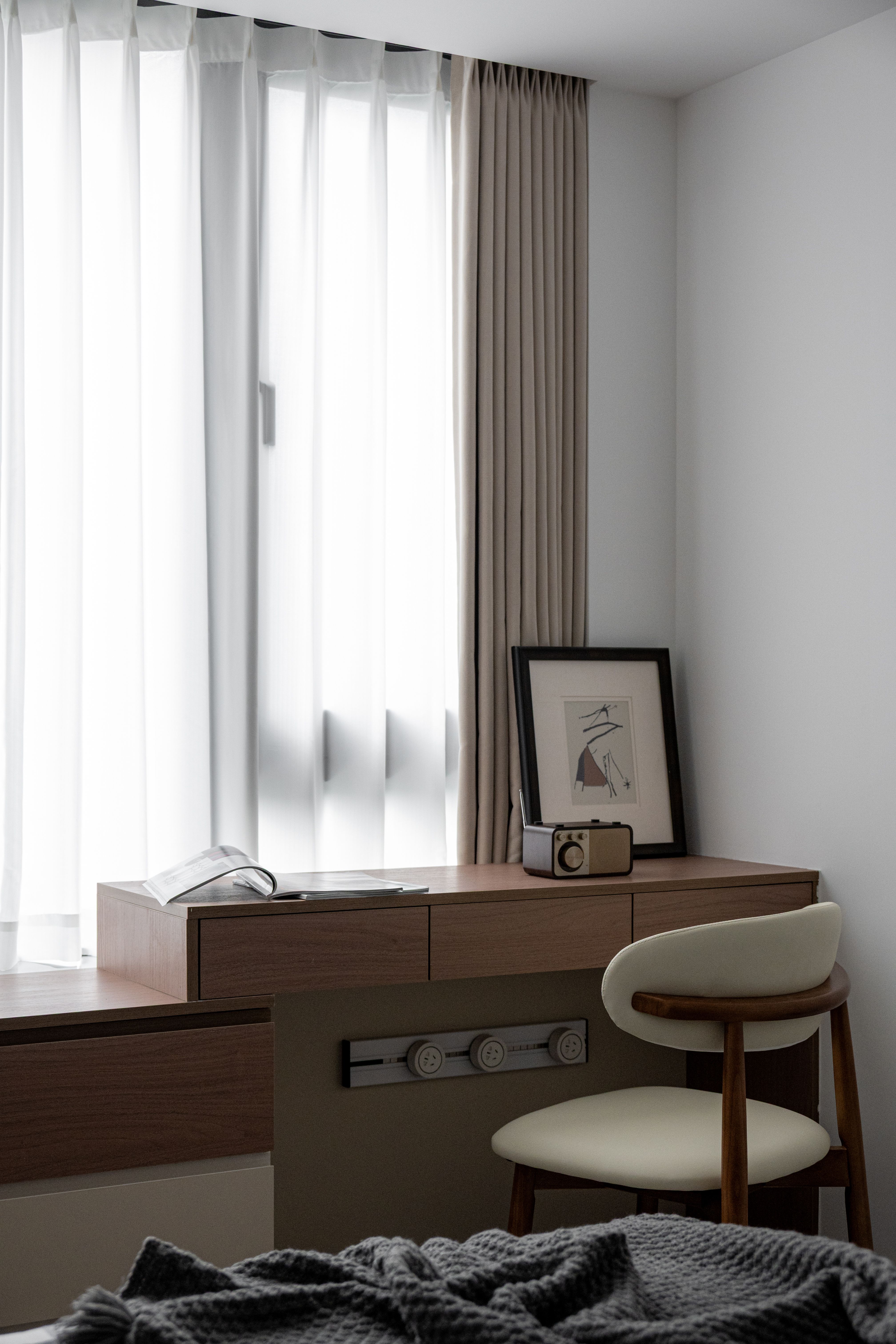 Mesa de home office iluminada por uma janela com cortina