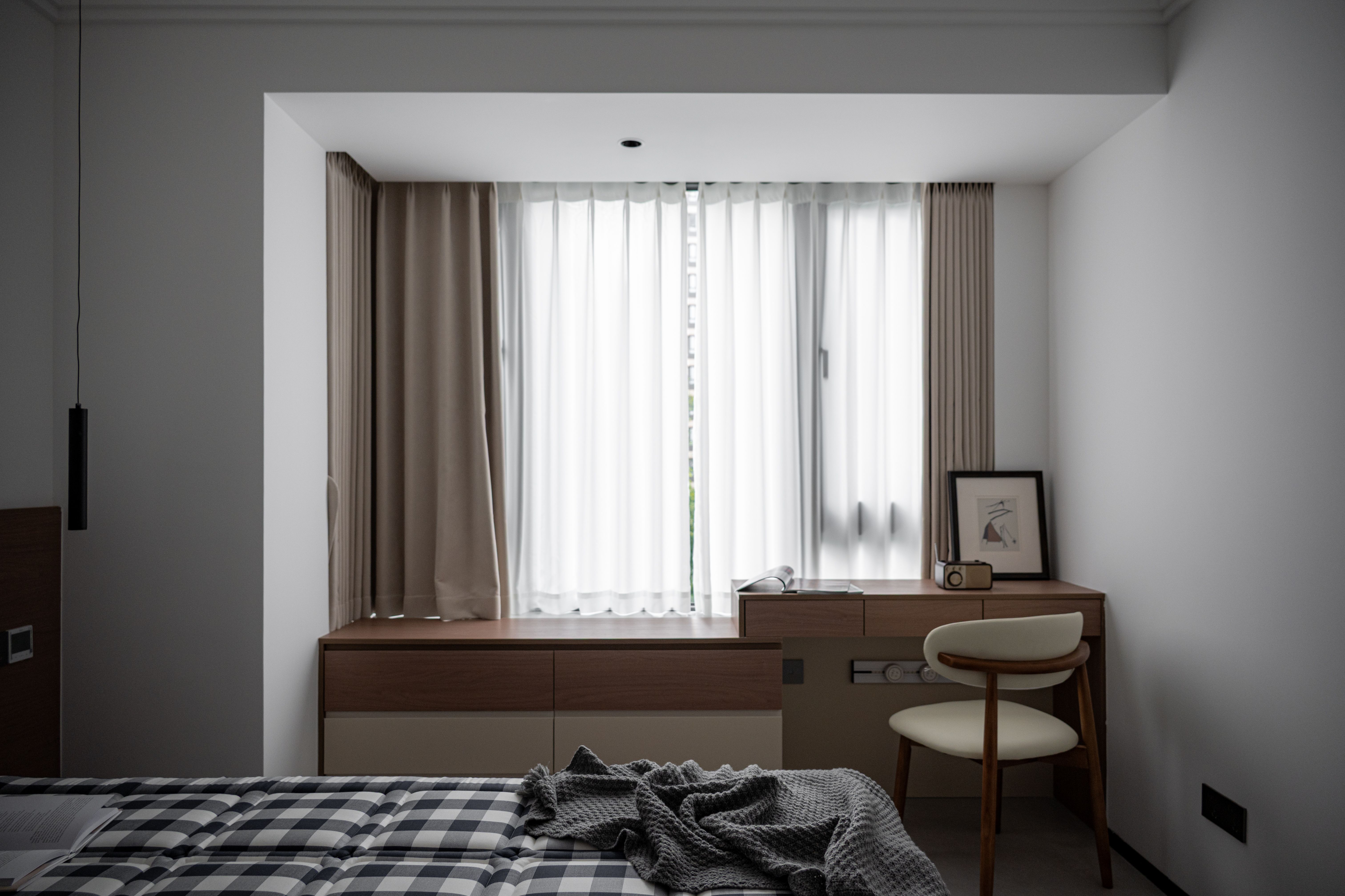 Small wooden desk placed by a bright bedroom window, ideal spot for a makeup vanity