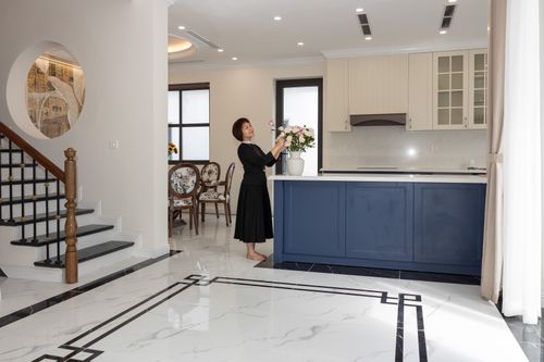Free Elegant open-plan kitchen with a woman arranging flowers adds a homely touch. Stock Photo