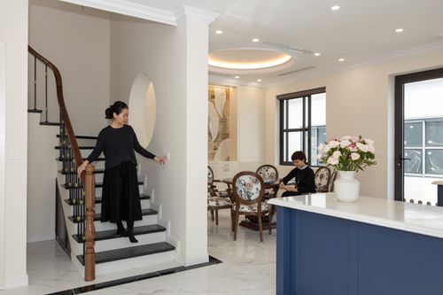 Free Chic and elegant modern home interior featuring a woman on stairs and another sitting at a table. Stock Photo