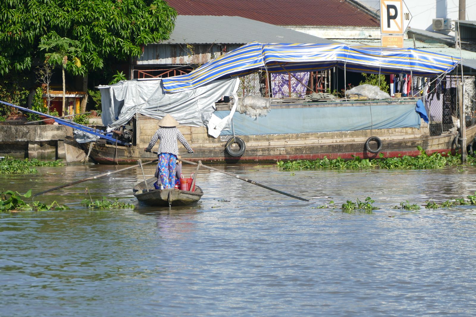 A person rowing a traditional wooden boat on the Mekong River at Ngã Năm, Vietnam