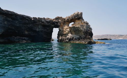 Free A captivating view of a natural rock arch formation over the clear blue sea in Malta. Stock Photo